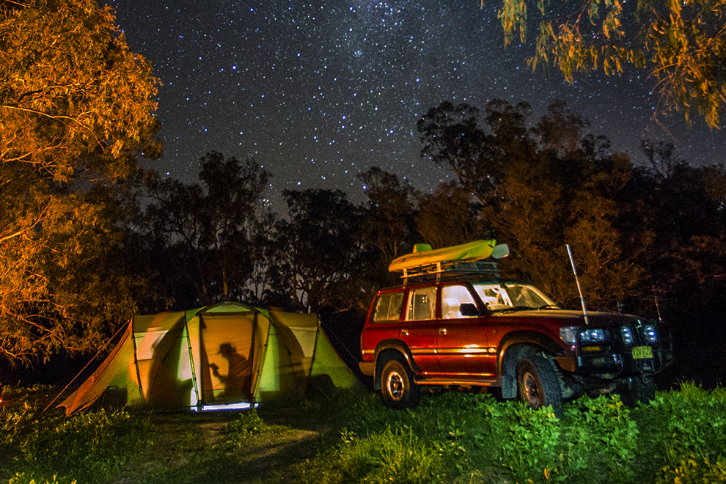 SUV parked next to a lit-up tent at night.