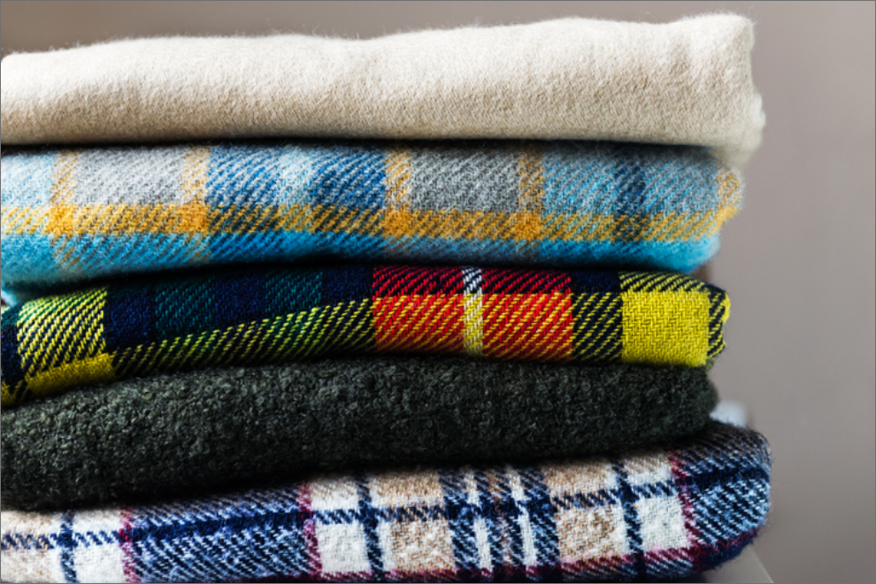 A neatly folded pile of multicolored fleece blankets.
